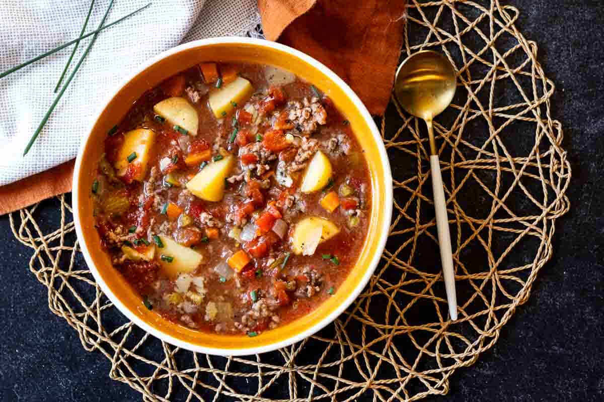 A bowl of hamburger soup with potatoes.