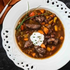 Red wine bean and beef soup in a shallow white bowl.