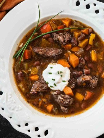 Red wine bean and beef soup in a shallow white bowl.