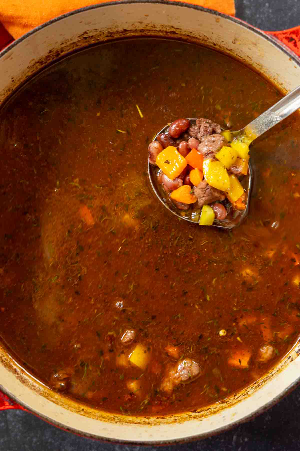 Adding vegetables to broth to make bean and beef soup.