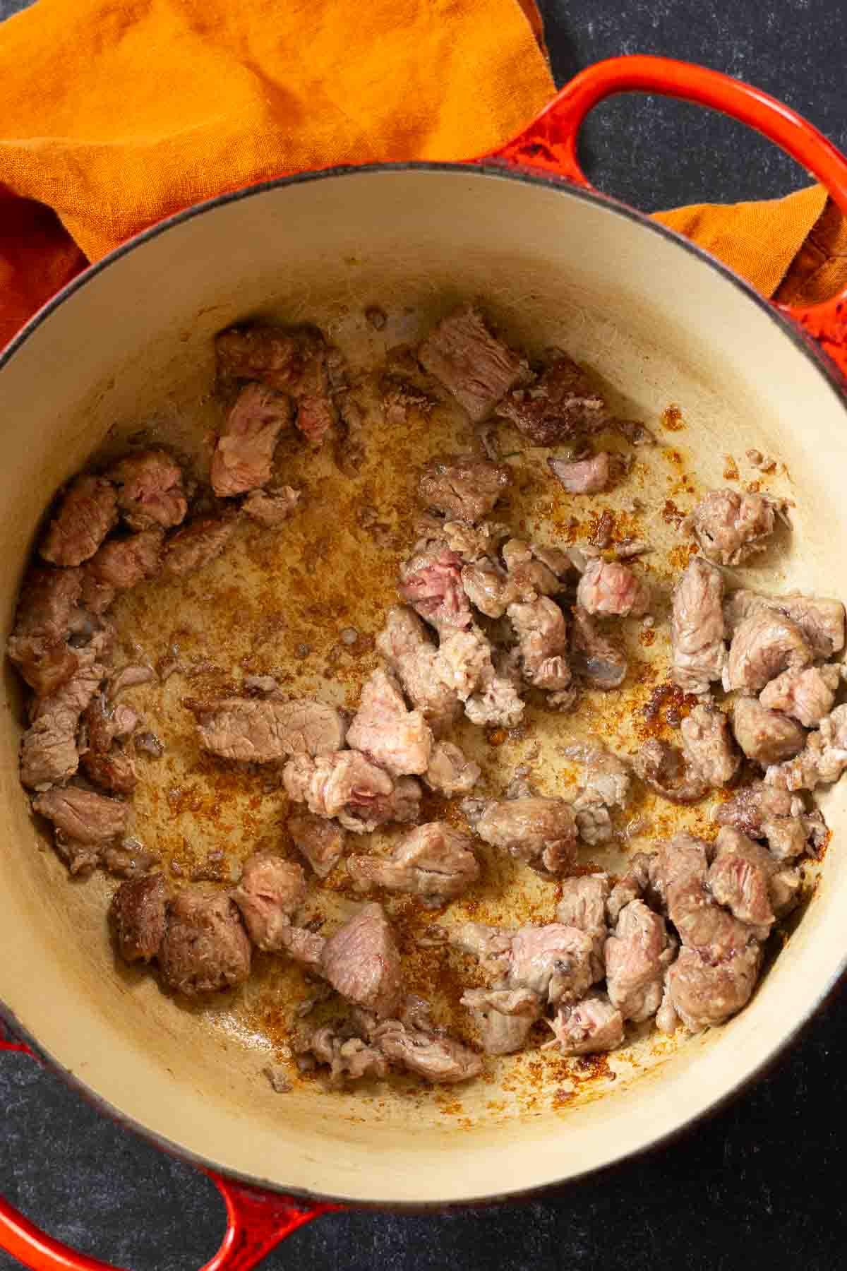 Browning chunks of beef in a dutch oven to make bean and beef soup.