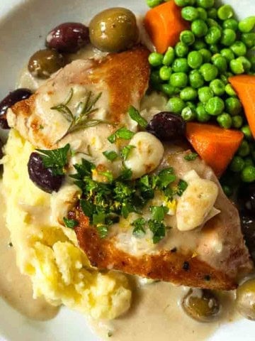 Chicken Veloute Supreme sauce served over chicken cutlets, mashed potatoes and with peas and carrots.