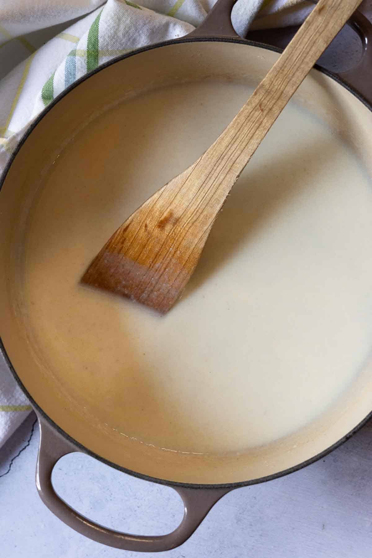 Adding flour to make a roux for white cheddar mac and cheese.