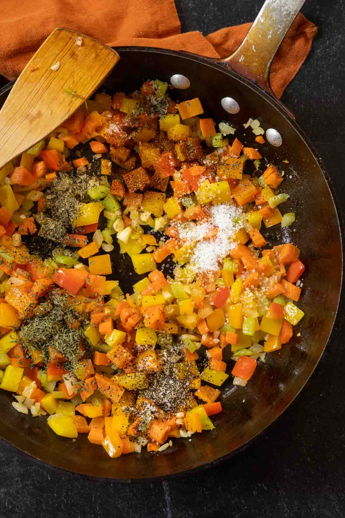 Adding seasonings to bell peppers and mirepoix to make bean and beef soup.