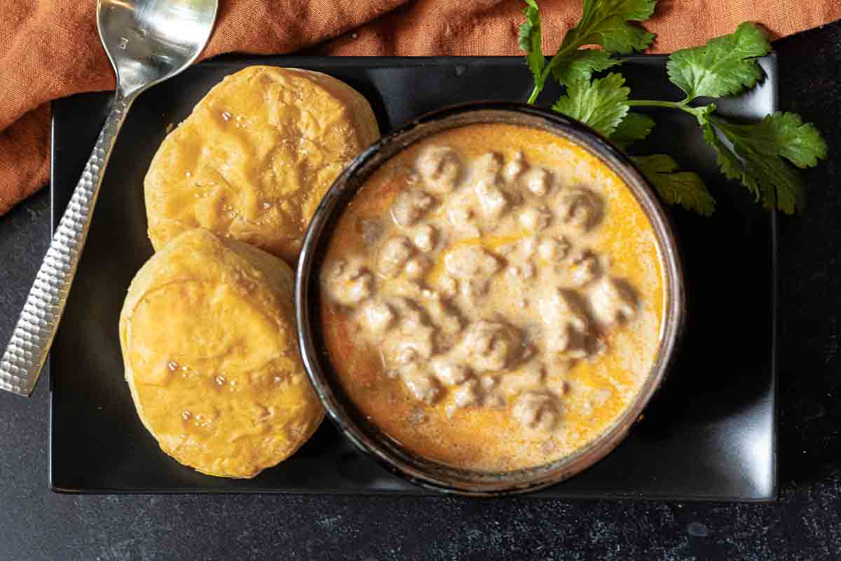 2 biscuits next to a bowl of chorizo gravy.