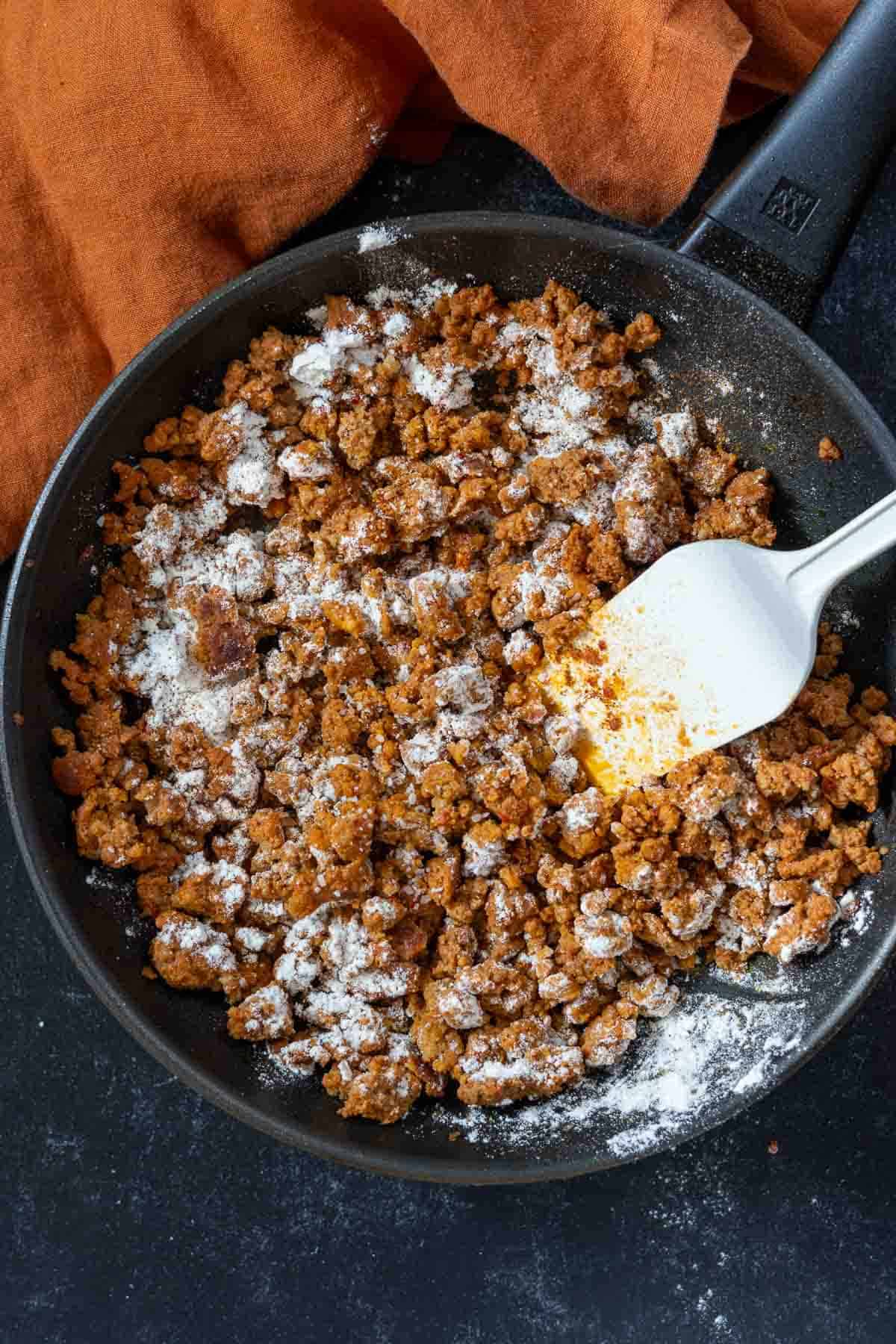 Adding flour to fried Mexican chorizo to make chorizo gravy.