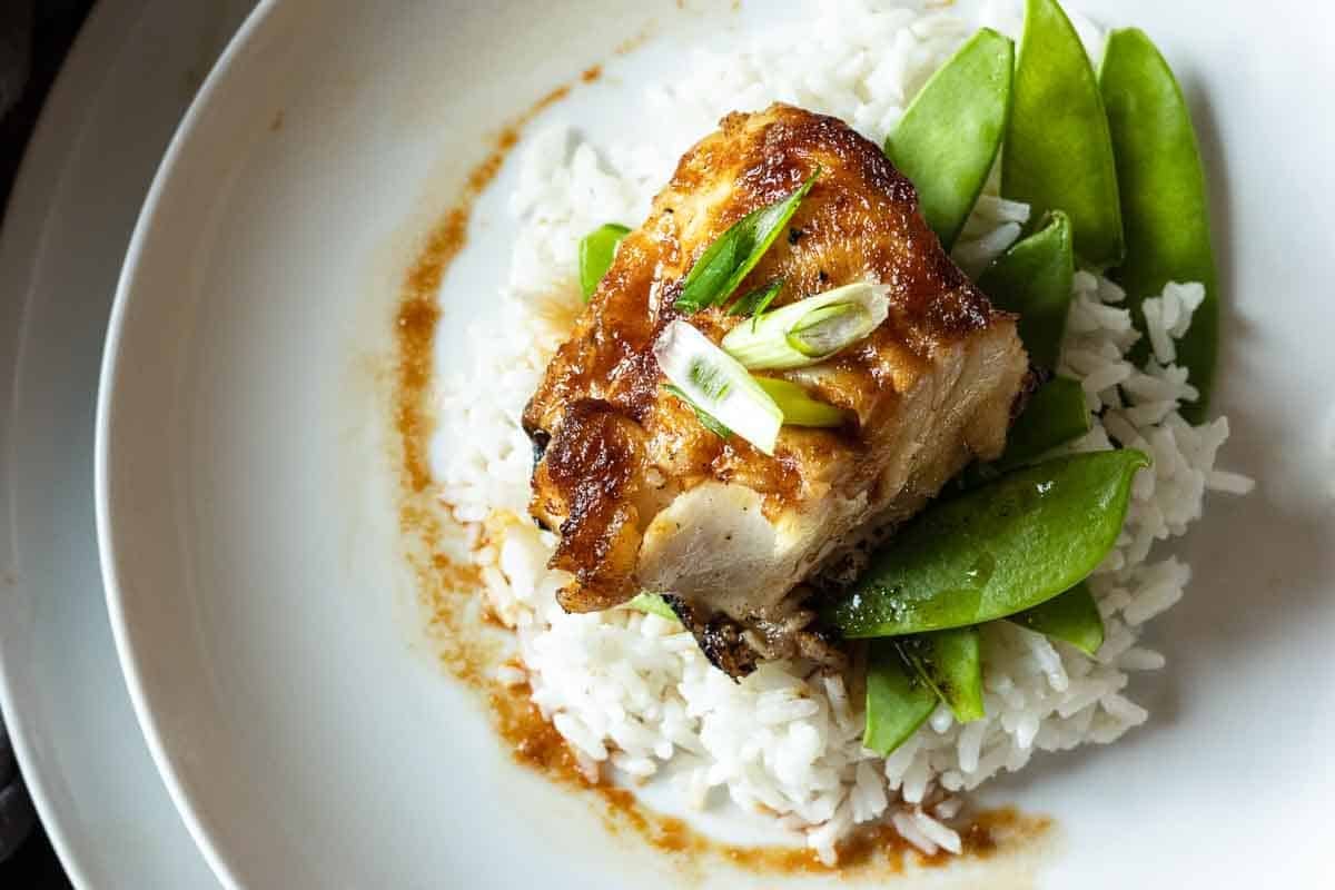 Pan Seared Sea Bass with a Sesame Ginger Glaze served over rice with snow peas.