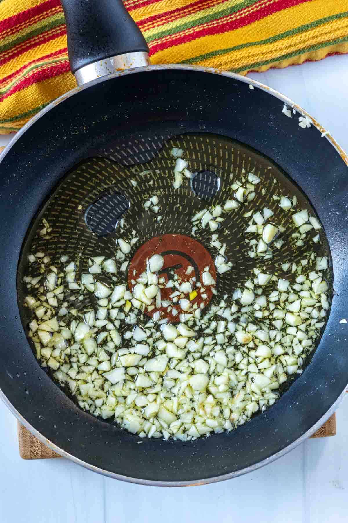 Cooking chopped garlic to make marbled potatoes.