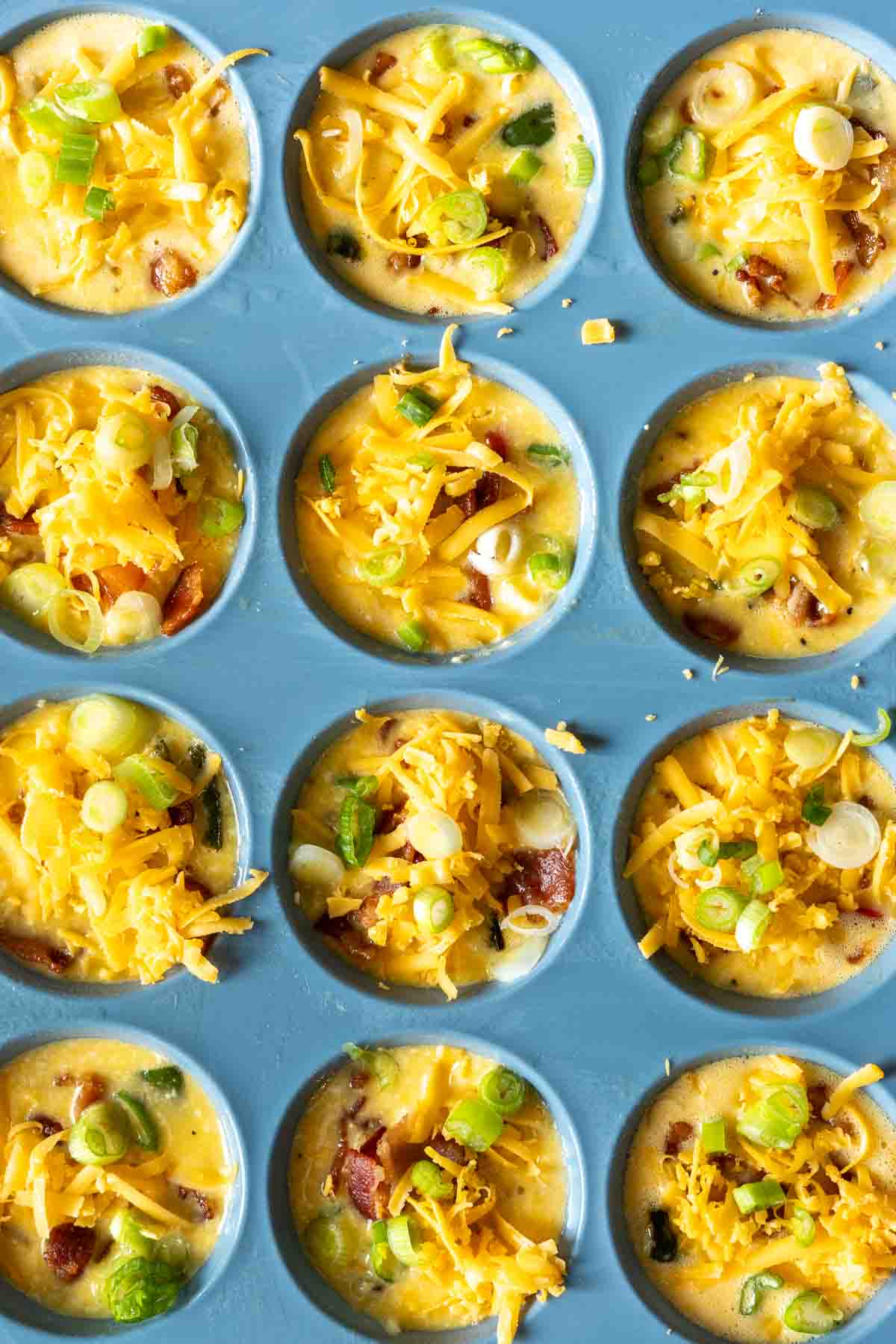 Adding grated cheese to the top of cottage cheese egg bites before baking.