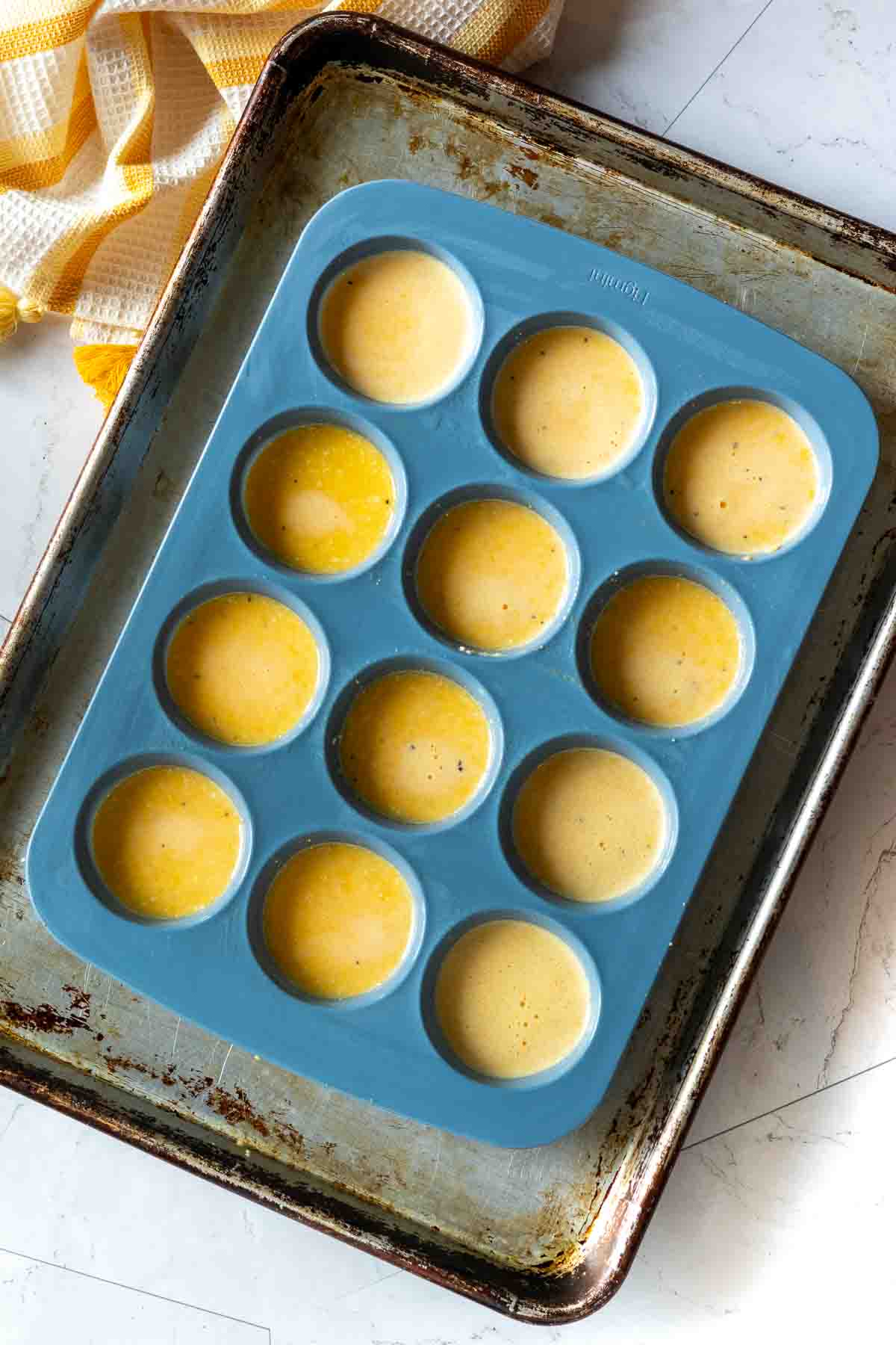 Filling a muffin tin with egg and cheese batter to make Cottage Cheese Egg Bites.