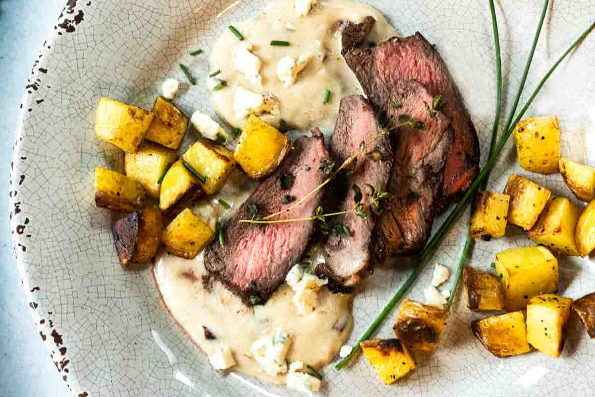 Pan seared Denver steak served with blue cheese sauce and cubed fried potatoes.