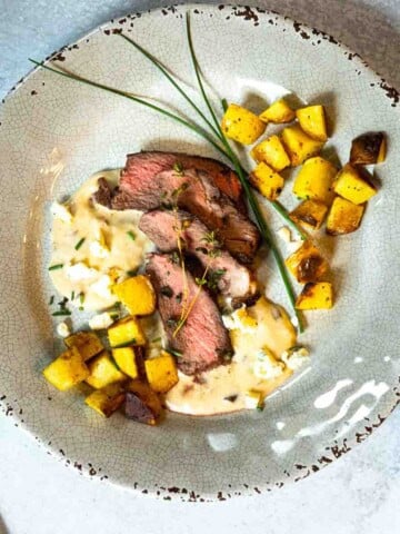 Denver steak with blue cheese sauce served with fried potatoes.