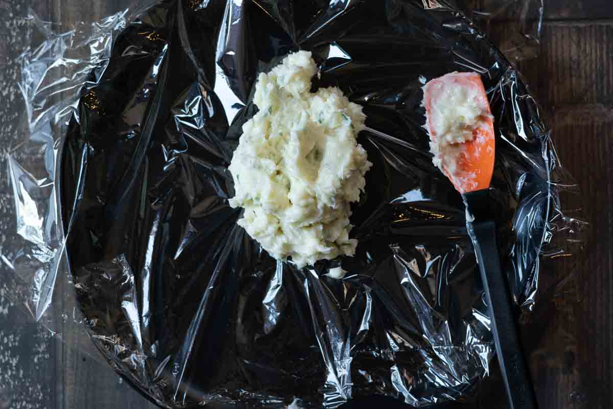 Rolling compound blue cheese butter into a roll using plastic wrap.