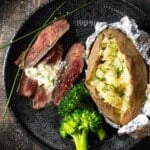 A pan seared merlot steak with blue cheese butter, served with a baked potato and broccoli.