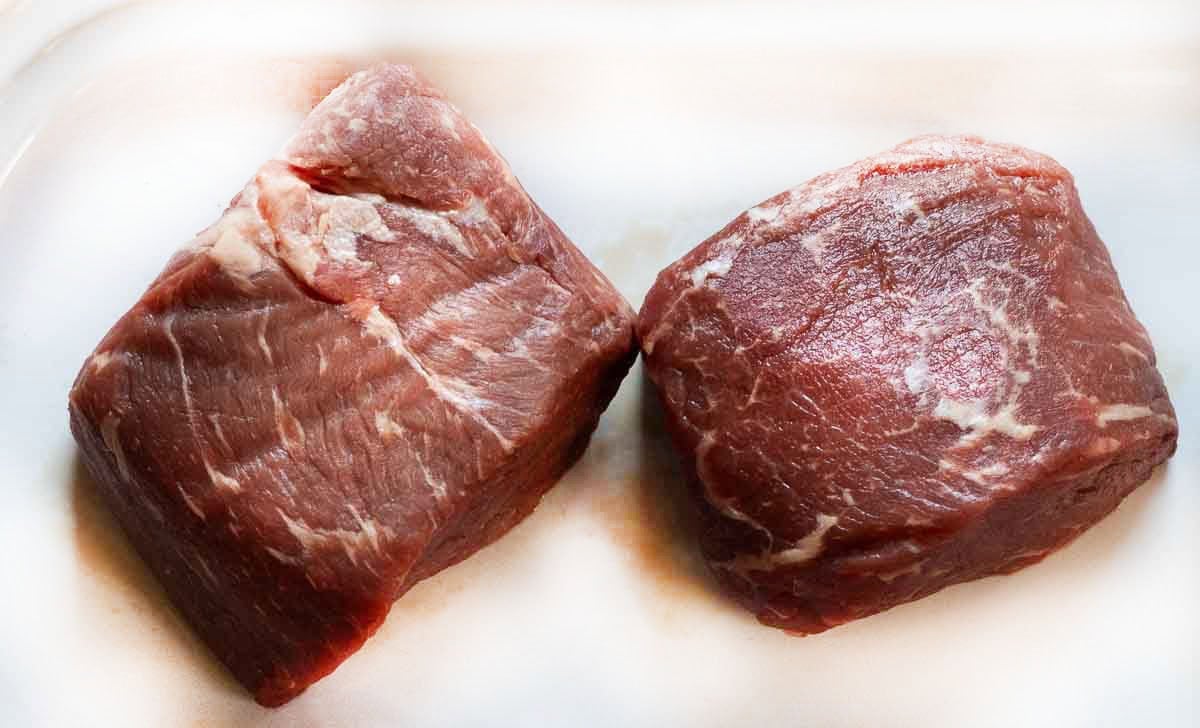 Two uncooked baseball top sirloin steaks.