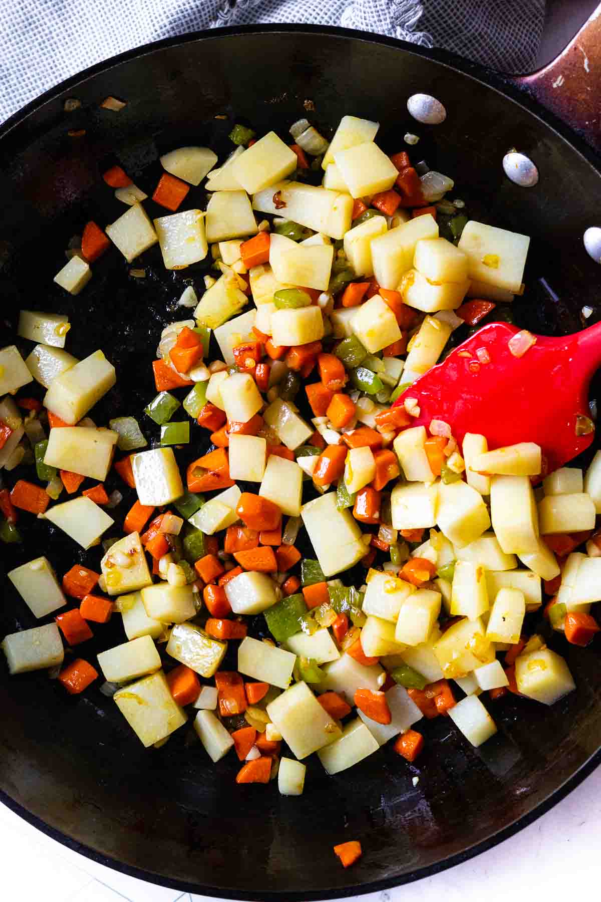 Step 5: Adding chopped potatoes to cooked vegetables.