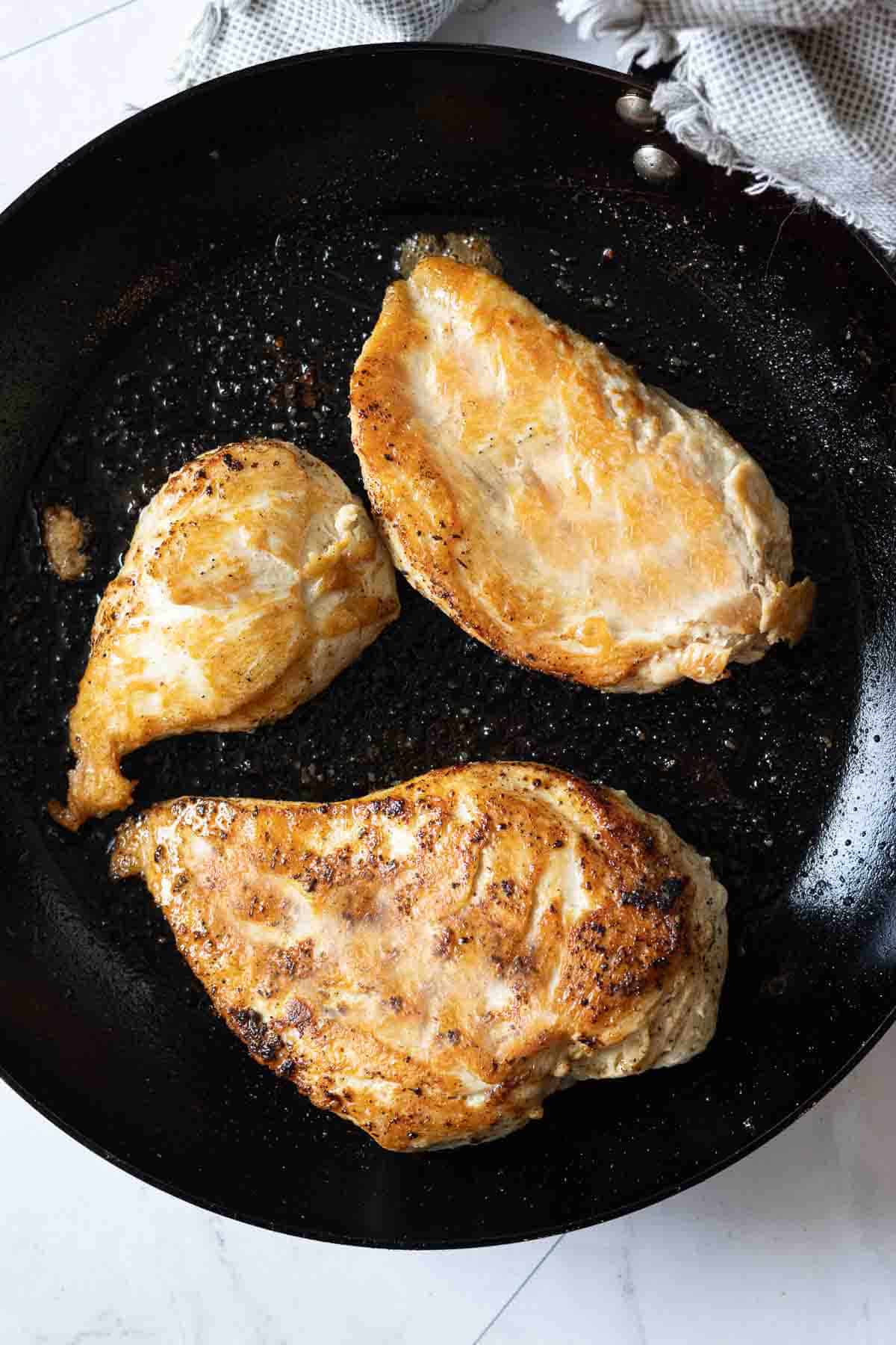 Searing chicken breasts to make chicken cabbage soup.
