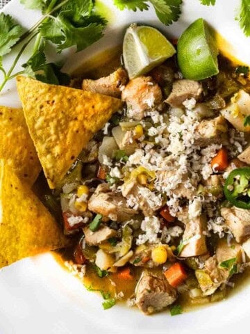 Spicy cabbage and chicken soup garnished with cilantro and corn chips.