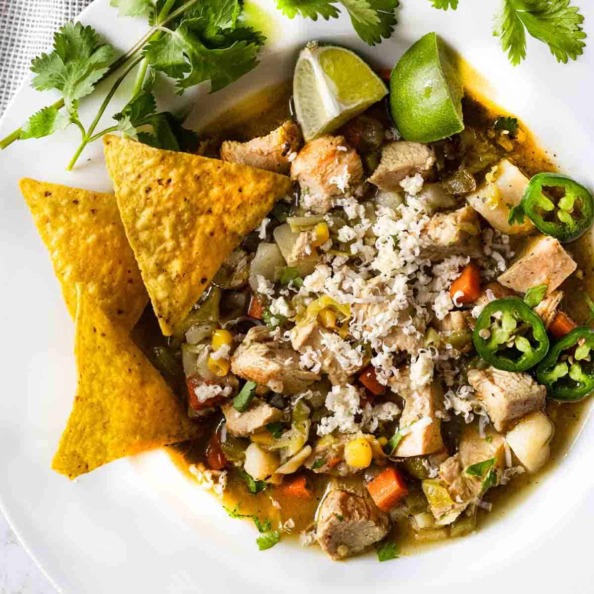 Spicy cabbage and chicken soup garnished with cilantro and corn chips.
