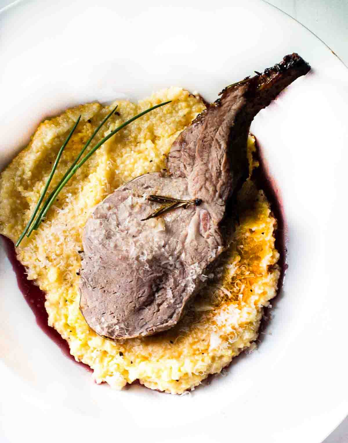 Roast rack of pork rib on a bed of polents and red wine.