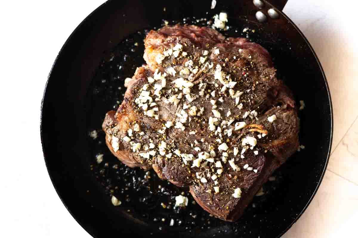 Step 3: Adding chopped garlic to a seared chuck eye roast.