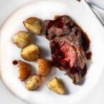 A slice of chuck eye roast on a plate served with roasted potatoes.