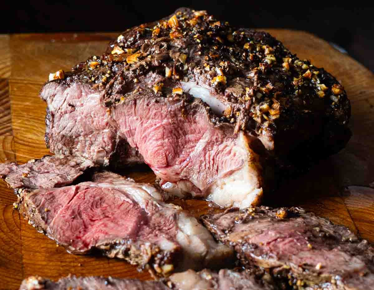 Cooked and sliced chuck eye roast on a wood cutting board.