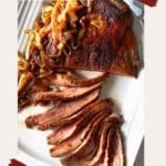 Cast iron flank steak, sliced and served on a white platter.