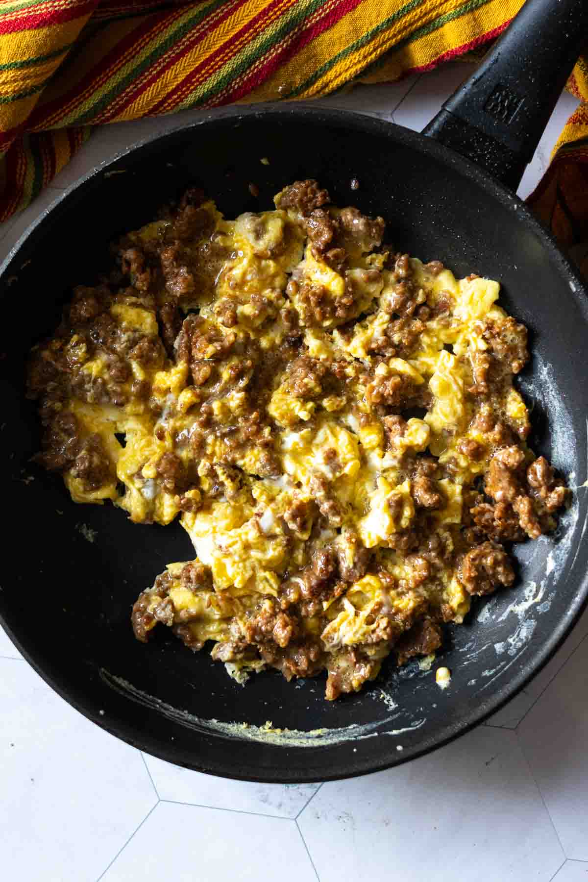 Adding eggs to cooked chorizo to make a chorizo breakfast burrito. Step 3.