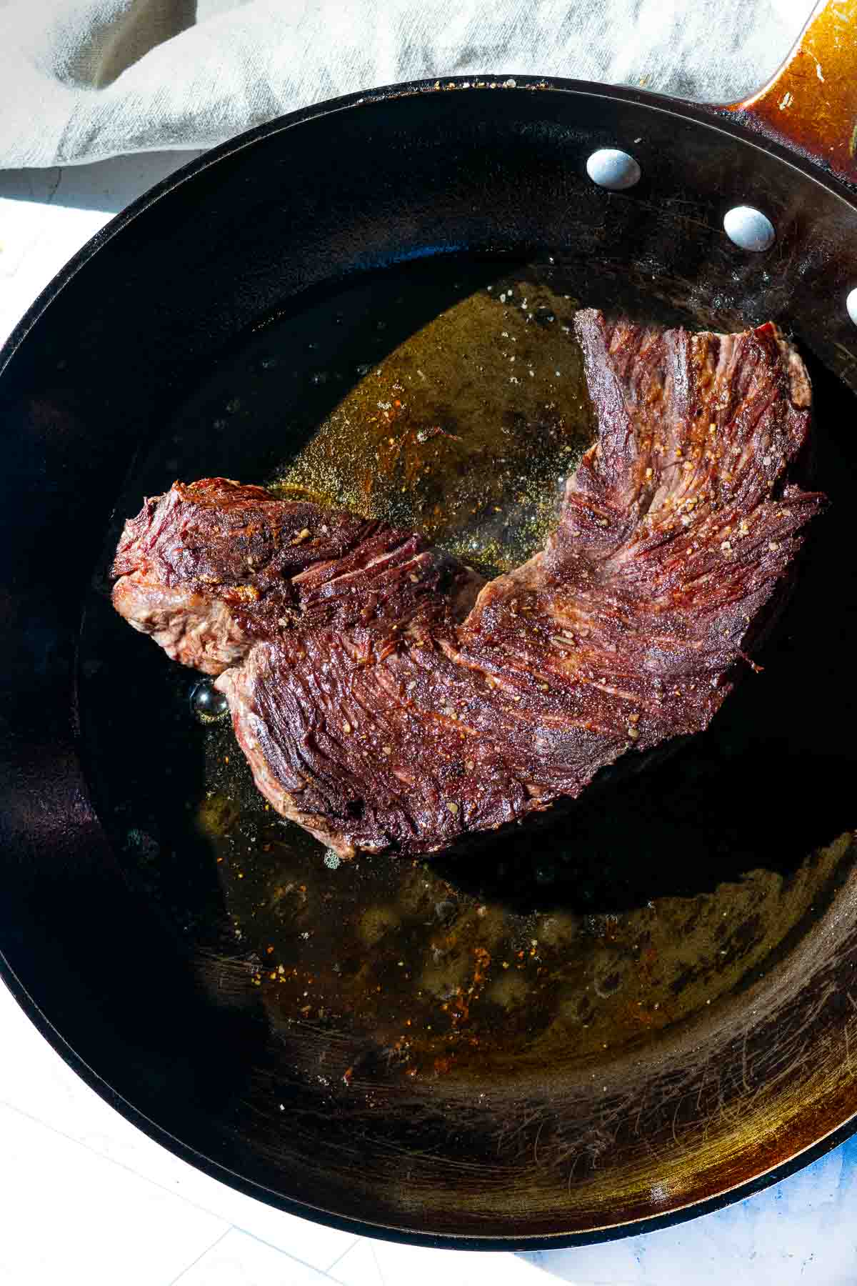 Cooking a hanging tender steak in a cast iron skillet.