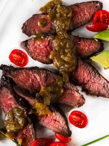 Hanging tender steak served with green chile sauce, tomatoes and avocado.